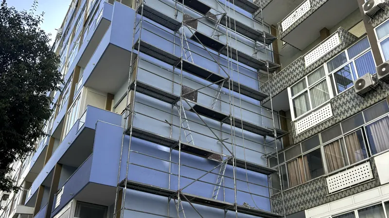Fachada azul de um prédio de vários andares com andaime