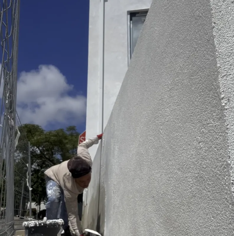 Pintor a trabalhar junto a uma parede branca texturada