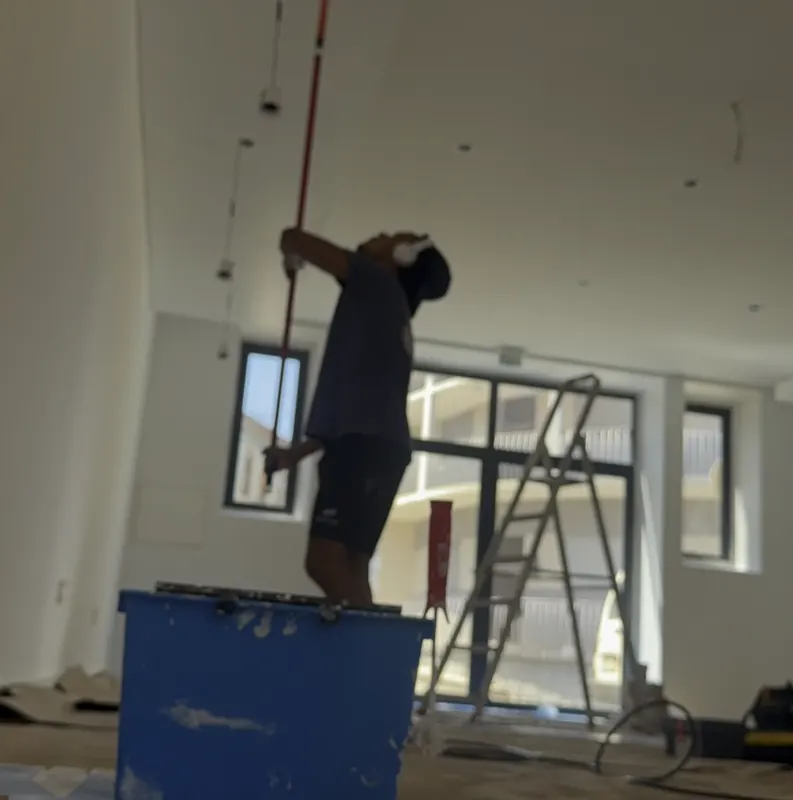 Pintor em cima de um caixote a pintar o teto