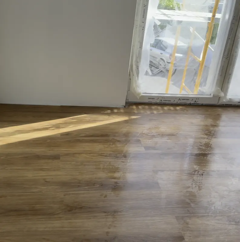 Pavimento flutuante cor de madeira numa sala com porta de varanda